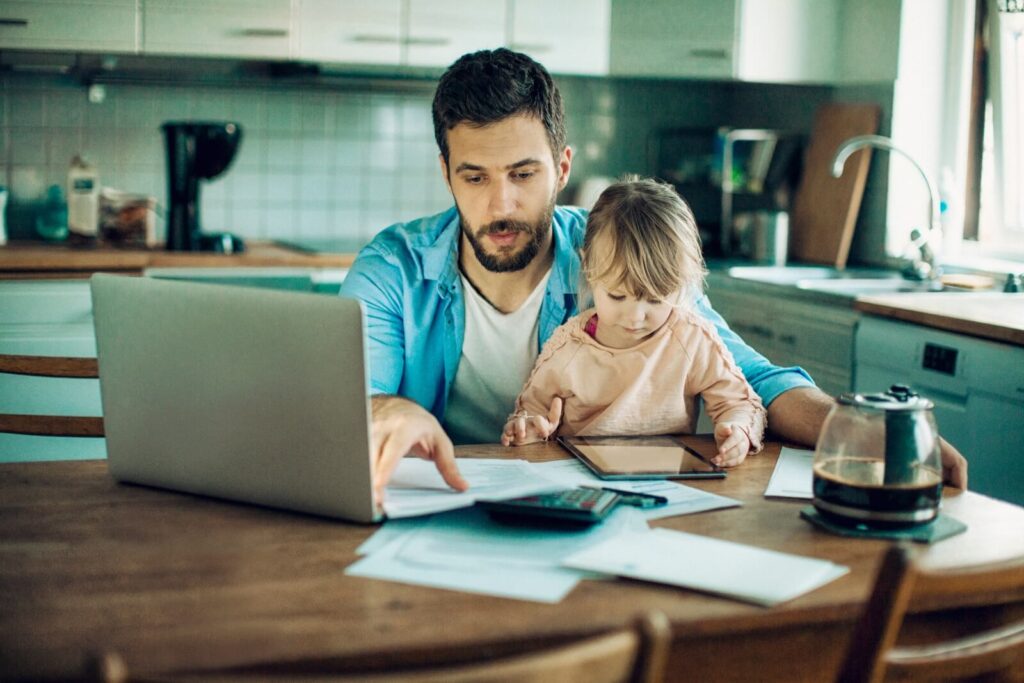 A father reviews bills and considers how a child support lawyer in Dayton, Ohio, might be able to help him