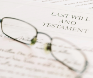Close-up of a last will and testament document with reading glasses, representing estate planning, probate law, and legal will preparation.